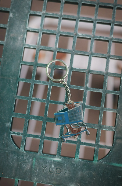Cartoon-like shopping cart keychain on a metal grate