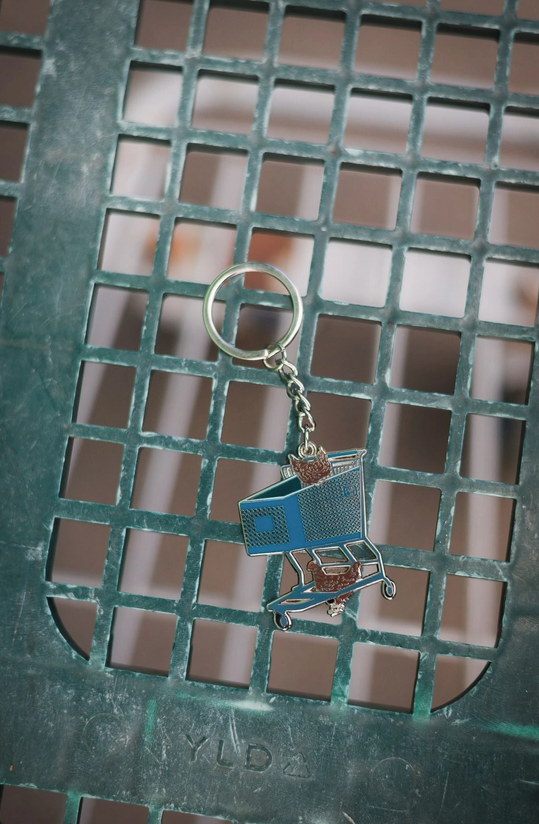 Cartoon-like shopping cart keychain on a metal grate