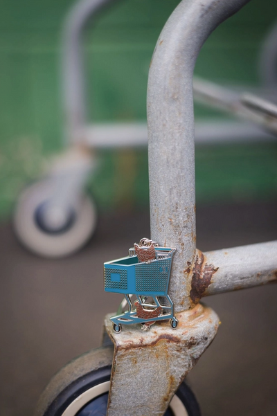 Small blue shopping cart attached to a rusted metal structure with a blurred background