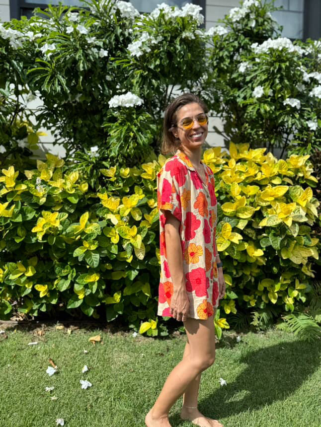 Woman in a colorful dress standing in front of green and yellow foliage