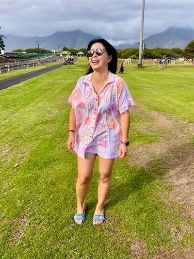 Woman in a colorful shirt standing on grass with mountains in the background