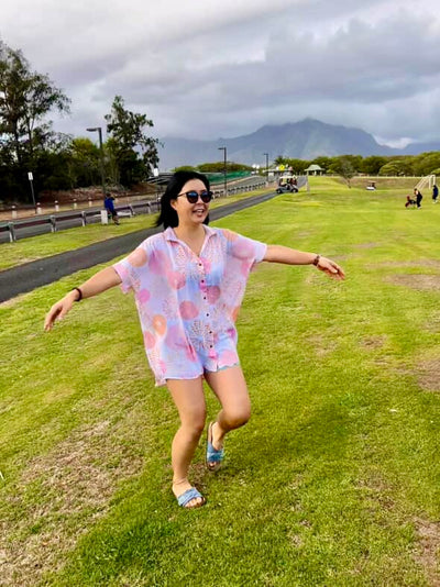 Woman in a colorful outfit running on grass with mountains in the background